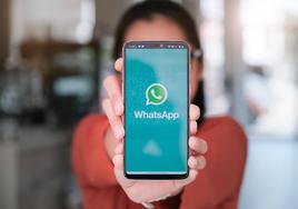 Una mujer sostiene un móvil en el que aparece la aplicación de WhatsApp.