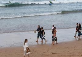 Varias personas caminan por la playa de San Lorenzo durante este viernes, último día de buen tiempo antes de que regrese la lluvia.