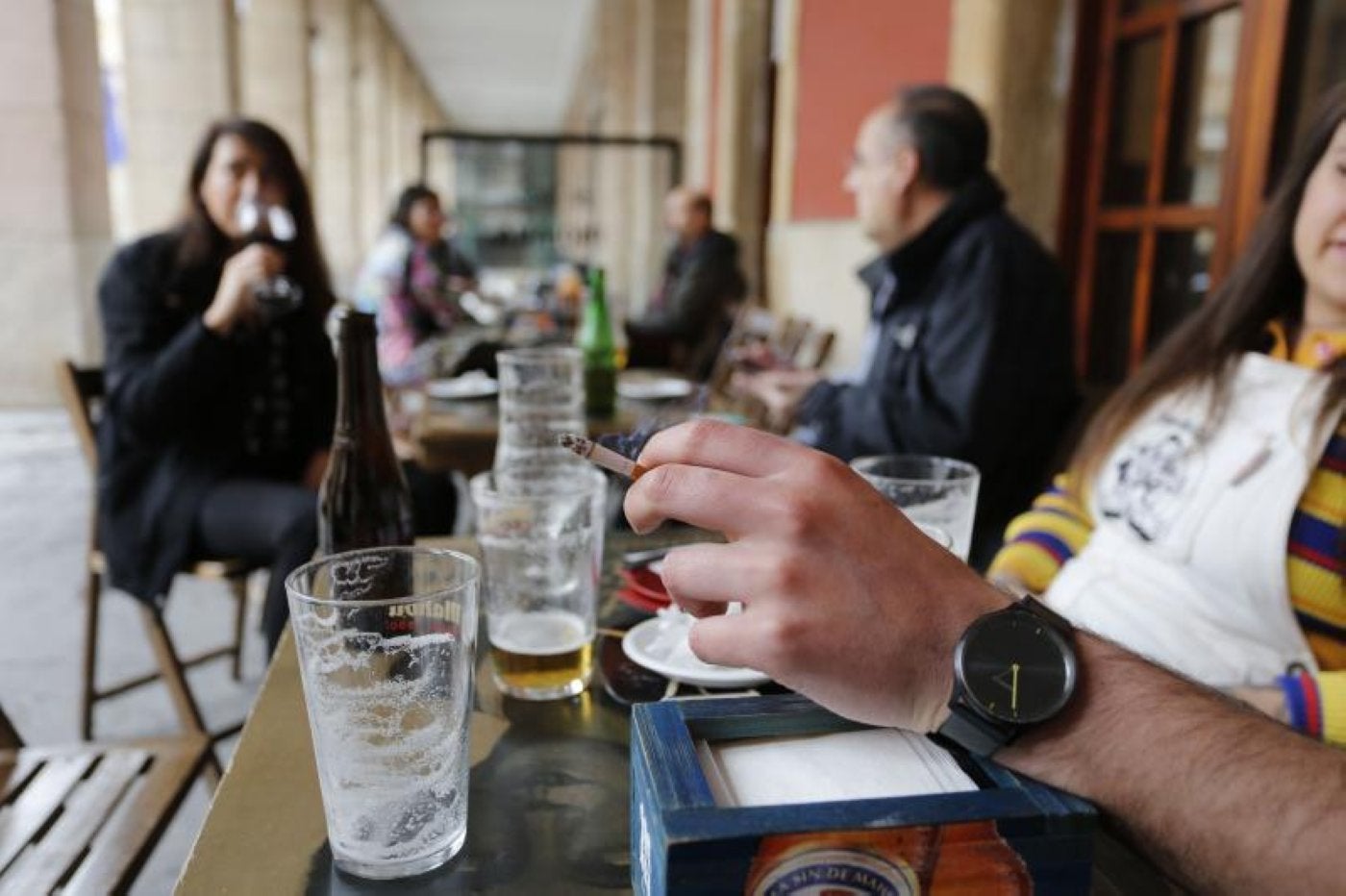 El cliente de un local hostelero de la plaza Mayor de Gijón, fumando en la terraza.