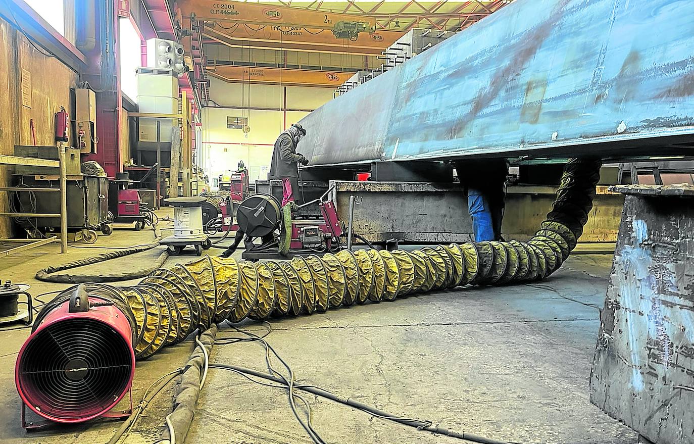 Un operario, al fondo, de la empresa Metálicas Estrumar, en Burgos, trabaja en una de las piezas de la colosal pasarela peatonal de Lugones y La Fresneda. a. f. g.