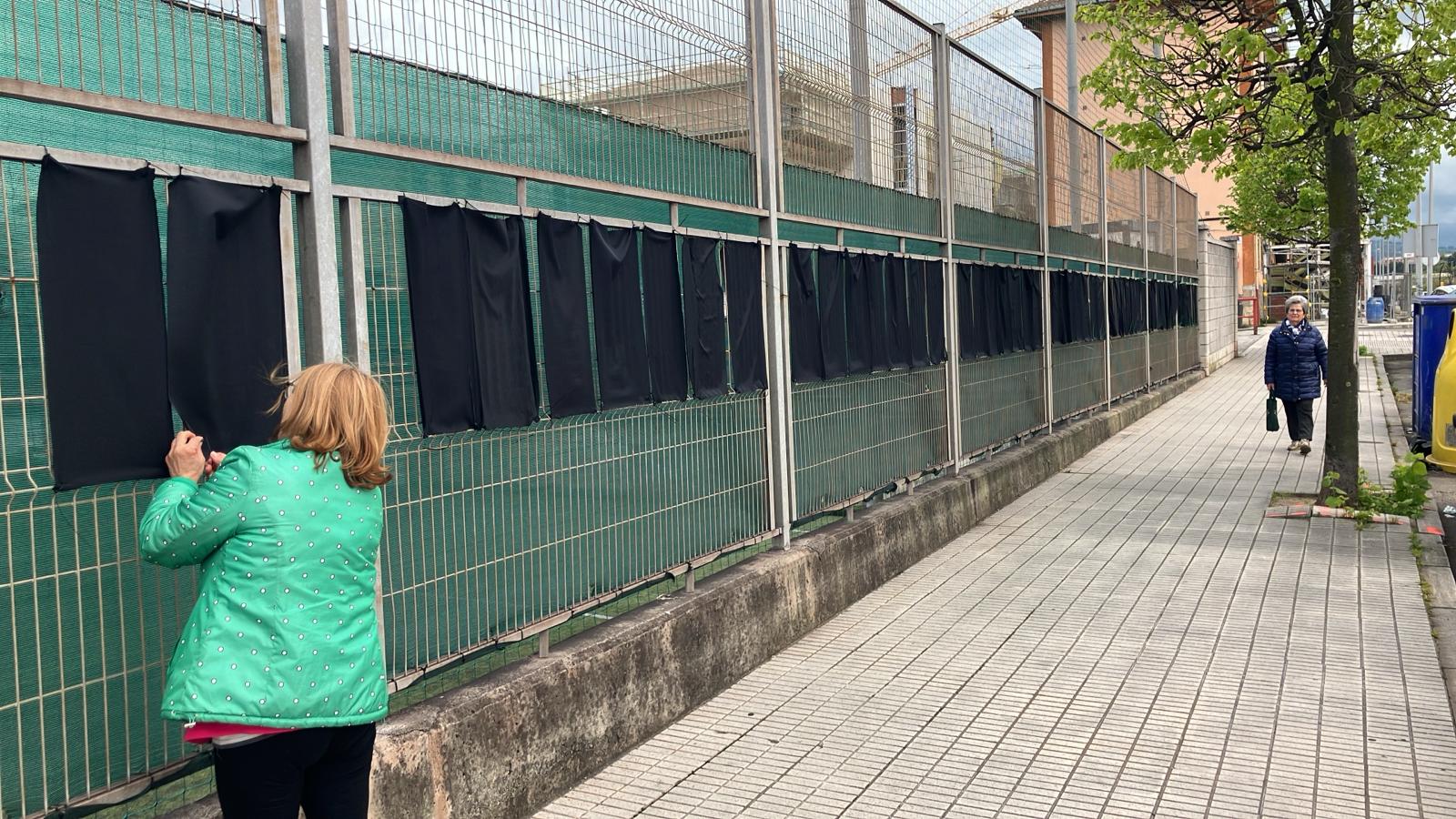 Colocación de los trapos negros alrededor del campo de fútbol de Lloreda, en Tremañes.