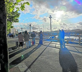 Un grupo de jóvenes turistas contempla la puesta del sol desde el paseo de Fomento de Gijón.