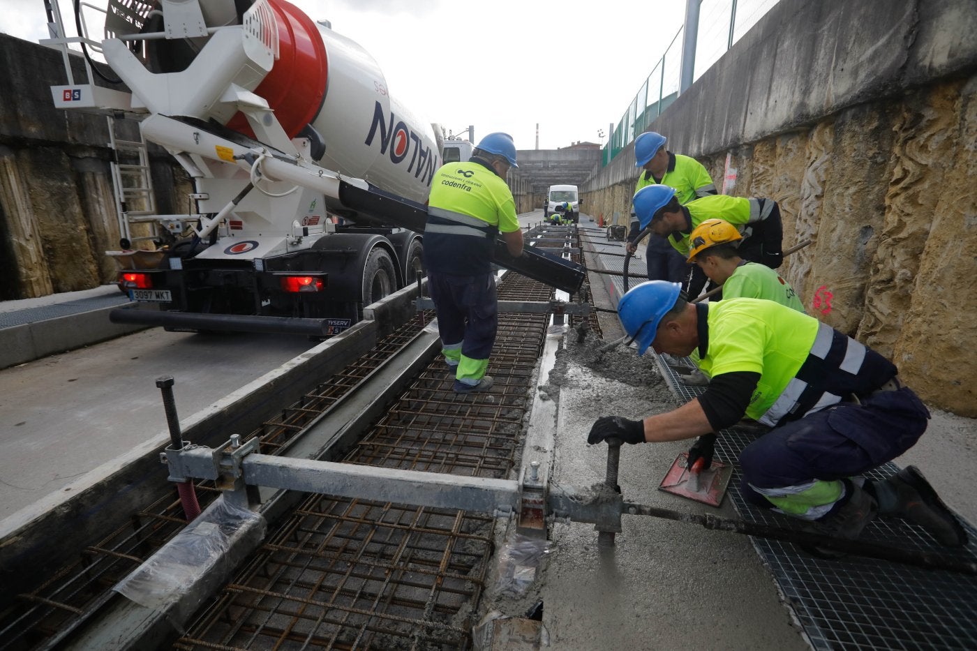 Los operarios reparten el hormigón por el pórtico de encofrado para crear la placa en la que irán los carriles .