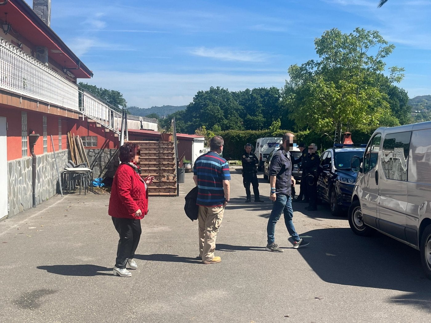 La propietaria del inmueble y casera de los sospechosos conversa con los agentes de la Policía Nacional, junto al jardín.
