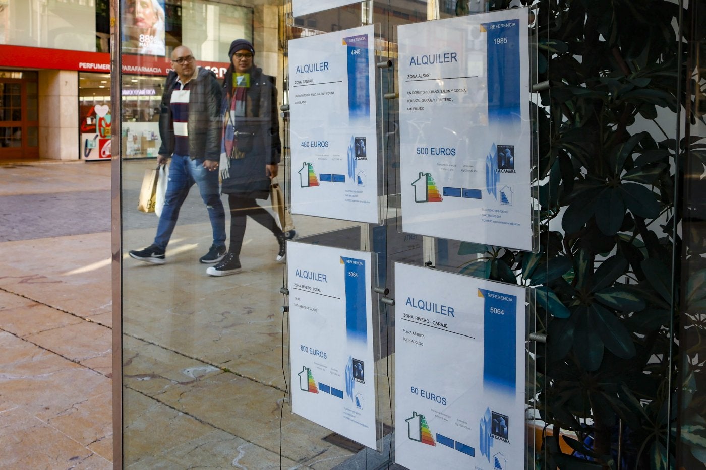 Una pareja observa el escaparate de una inmobiliaria mientras pasea por la calle La Cámara, en Avilés.