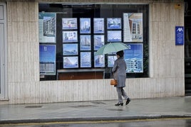 Una mujer observa el escaparate de una agencia inmobiliaria en Gijón.