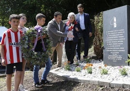 Los escolares Antonio García, Luz Álvarez y Olegario Díaz dejan la corona de flores en el memorial de La Sota, acompañados del alcalde de Laviana, Julio García, una familiar de una víctima, Maribel Morán, y el presidente de Hunosa, Enrique Fernández.