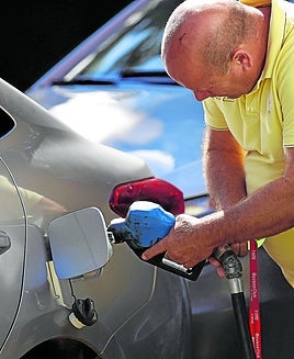 Un hombre echa gasolina en su vehículo.