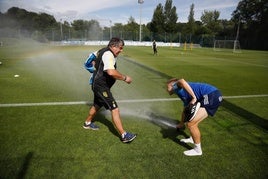 Alemao bromea con los aspersores con un auxiliar antes del entrenamiento.