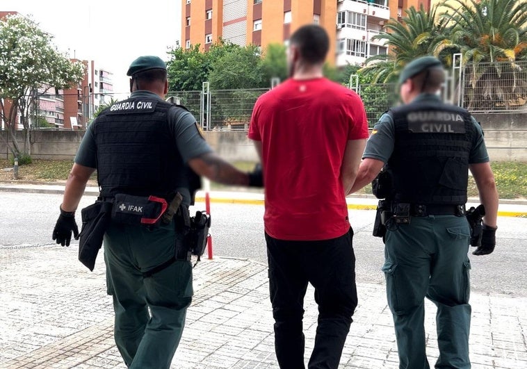 Dos guardias civiles con el preso fugado tras su detención en Barcelona.