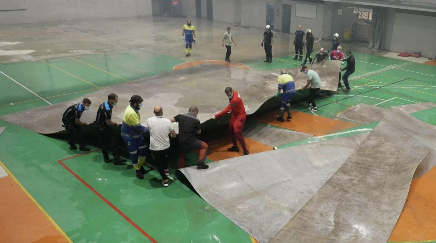 Retirada de parte del suelo verde de la pista central del polideportivo El Masgaín, en Pola de Lena.