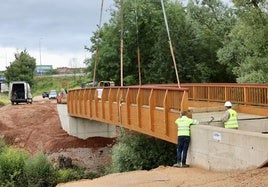 Operarios trabajan en la colocación del puente de madera sobre el río Noreña.