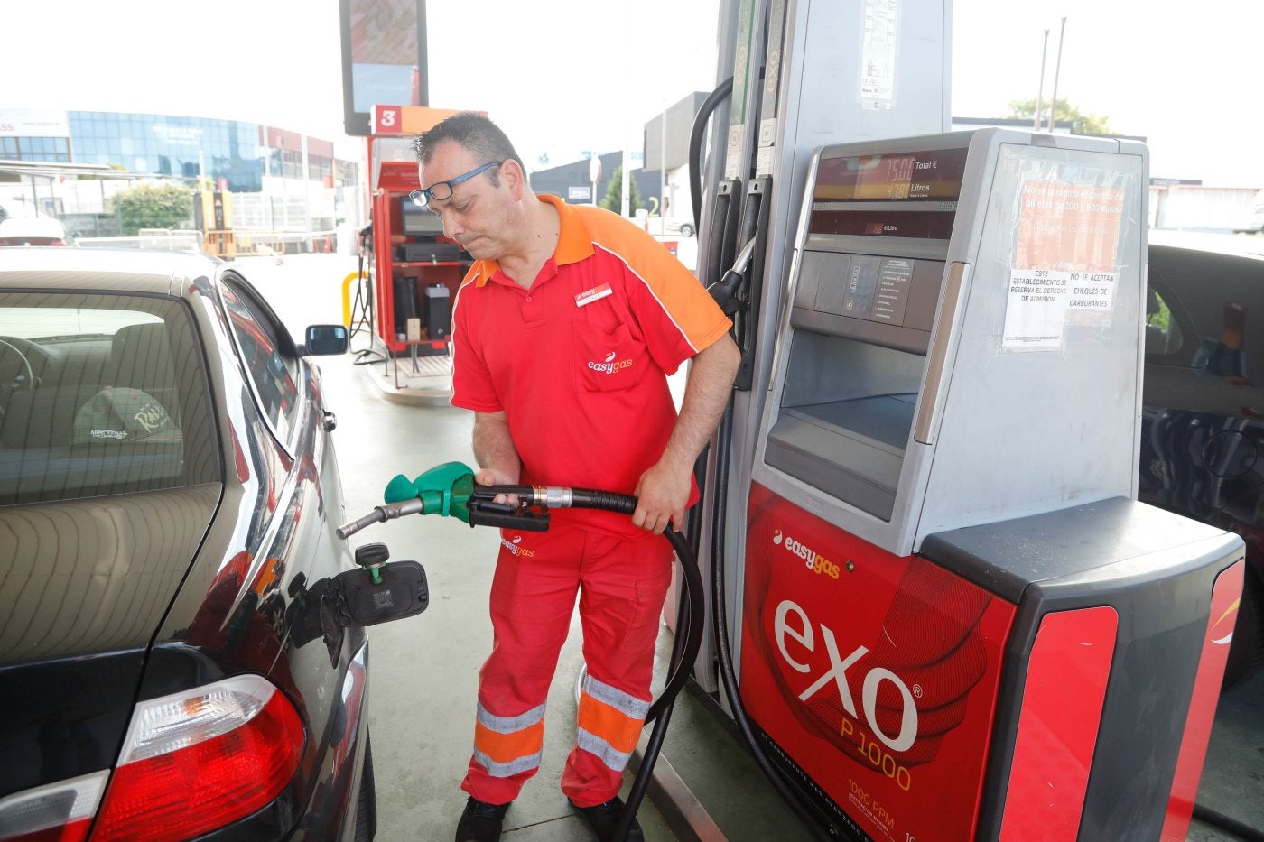 Un trabajador de una estación de servicio carga el depósito de un vehículo.