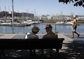 Tres mayores junto al puerto deportivo de Gijón en un día de verano del pasado año.