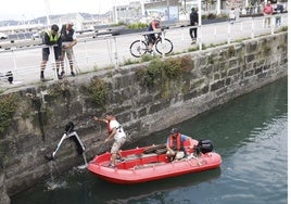 Recogida de uno de los patinetes arrojados al agua en el Puerto Deportivo, que han quedado inutilizados.