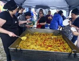 Lourdes Noval, en el centro de la imagem supervisa el reparto de la paella.