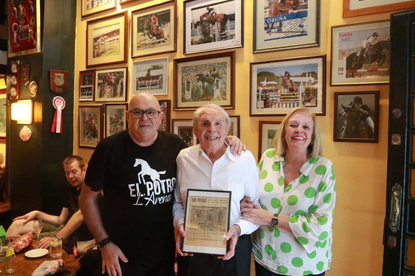 Agustín, José Manuel y Luci Buznego, con la página enmarcada de EL COMERCIO de hace 50 años, cuando abrió el bar.