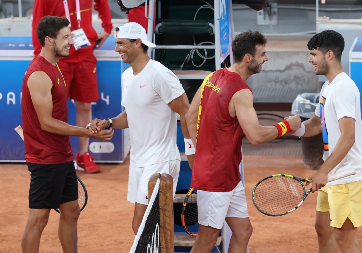 Pablo Carreño, a la izquierda, saluda a Rafa Nadal, mientras su compañero Marcel Granollers hace lo propio con Carlos Alcaraz tras el set de entrenamiento que disputaron antes de su debut el sábado en los Juegos.