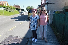 Purificación Bedriñana, presidenta de la asociación de vecinos de Roces, e Iluminada Fernández, en la parada de autobús para la que reclaman un semáforo. En el tramo se puede apreciar el flujo de tráfico.