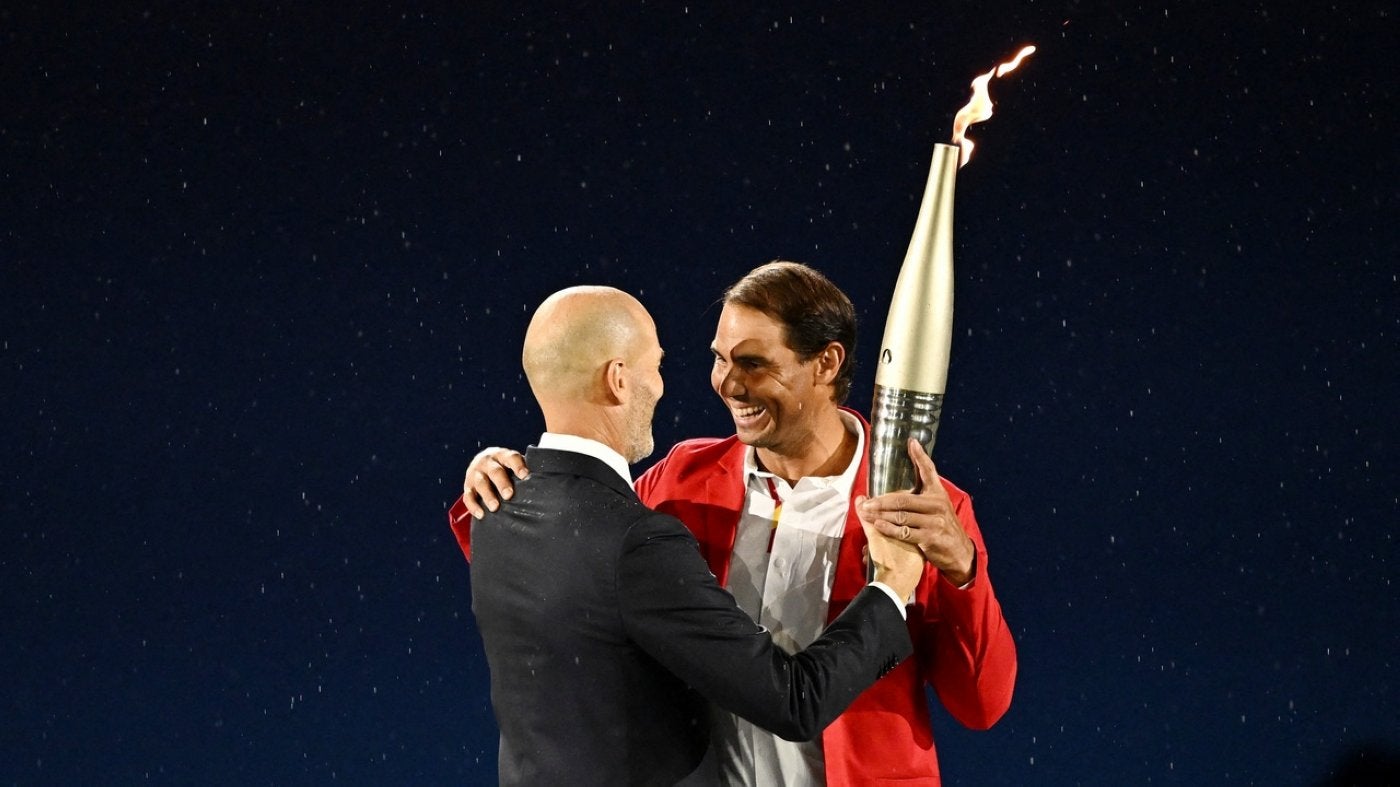 Zinedine Zidane entrega la antorcha olímpica a Rafael Nadal en la ceremonia de inauguración.