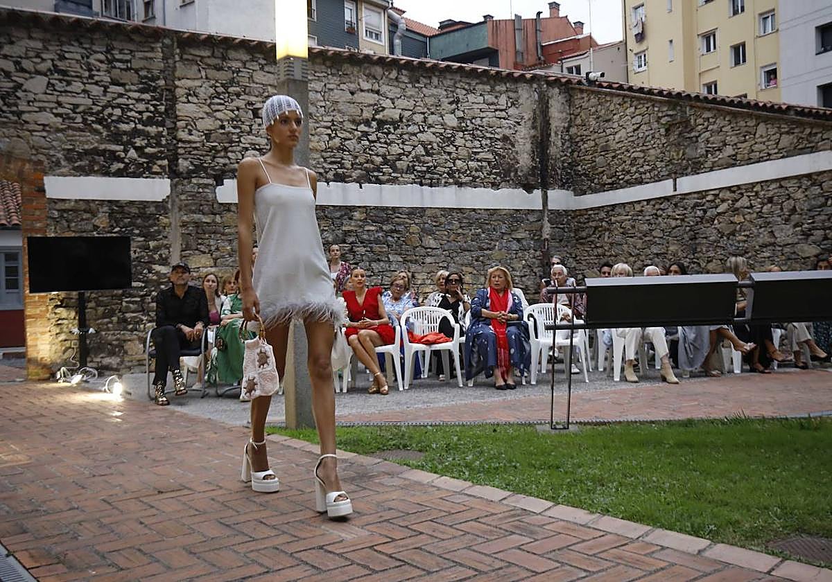 Una de las modelos de Piano B luce un vestido blanco decorado con plumas.