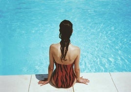 Una mujer, sentada al borde de una piscina.