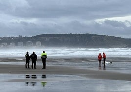 Dos socorristas, junto al cuerpo en San Juan, observados por Policía y Guardia Civil.