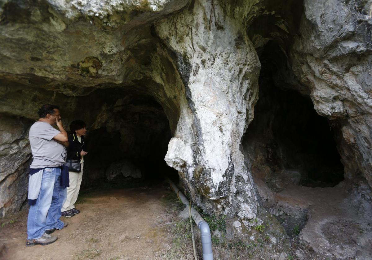 Dos personas visitando la cueva de la LLuera, que contiene grabados de animales.