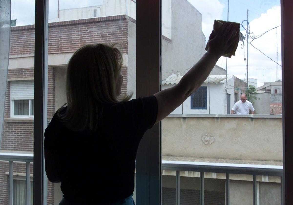 Una empleada del hogar limpiando una ventana.