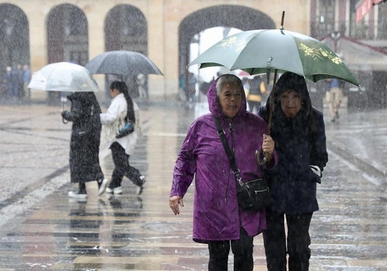 Dos mujeres, bajo la intensa lluvia este jueves en Gijón.