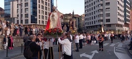 La procesión de la Soledad avanza por la calle Claudio Alvargonzález guiada por los rezos de Javier Gómez Cuesta. A la derecha, primer plano de la Virgen.