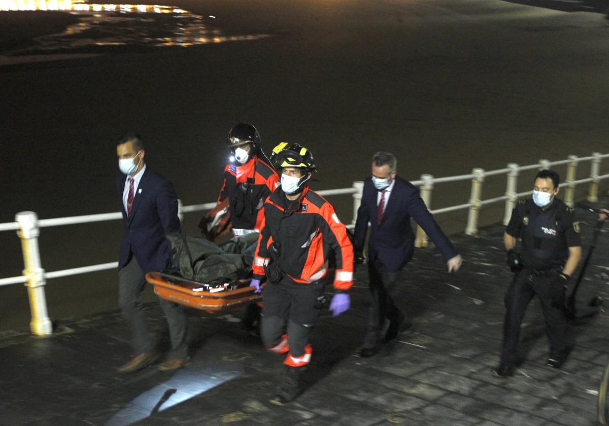 Bomberos y servicios funerarios trasladan el cadáver del joven ahogado en la playa de San Lorenzo, el 24 de junio de 2020.