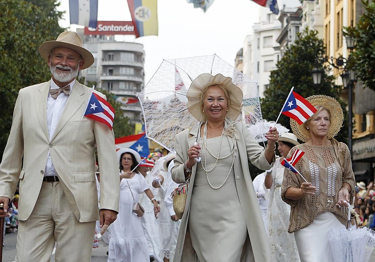 Una representación de indianos ondeando la bandera de Puerto Rico durante la 72 edición del desfile del Día de América en Asturias a su paso por la calle Uría.