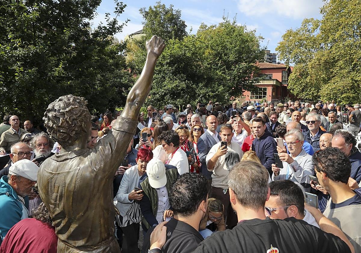 Aficionados e invitados tratan de hacerse una fotografía con la estatua de Quini al término del acto.
