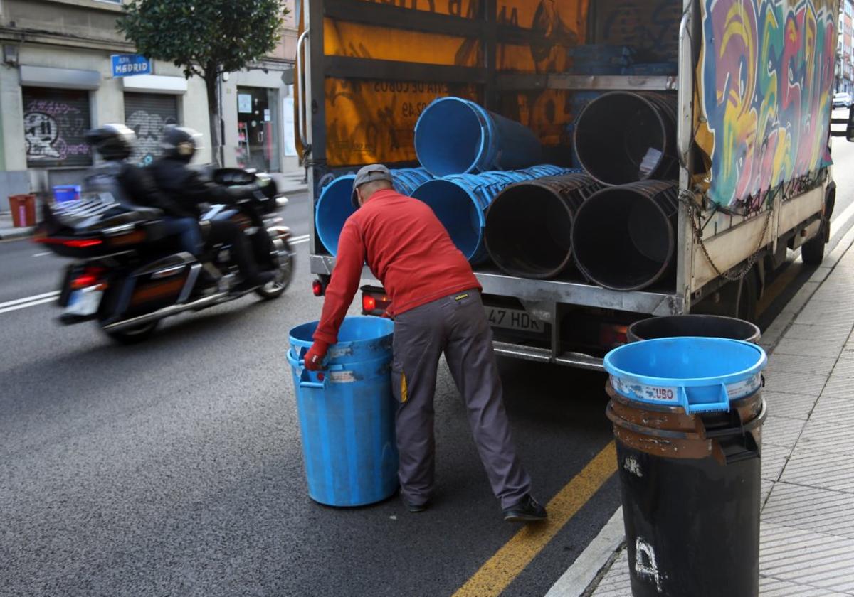 Un operario coloca los cubos para la recogida de basura en la avenida de la Tenderina.