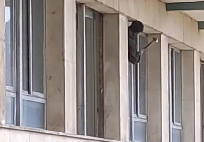 Un hombre con un martillo, en una de las ventanas del viejo hospital.