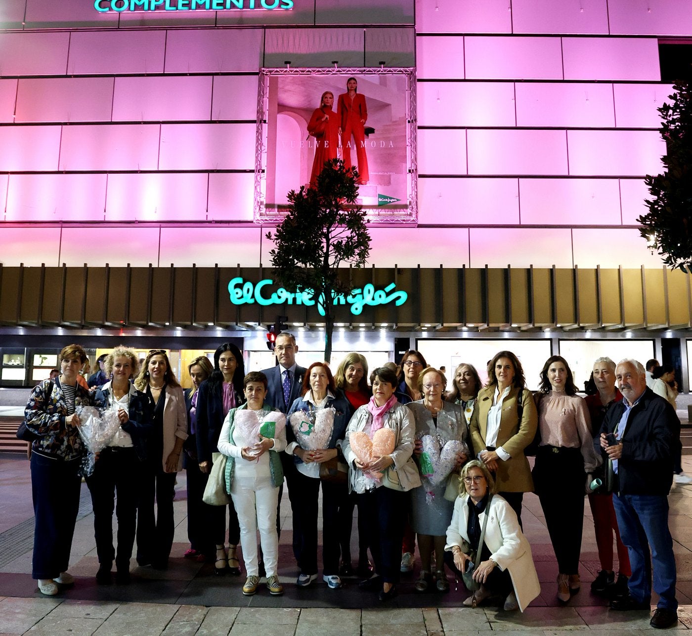 Los participantes, ante la fachada iluminada de rosa.