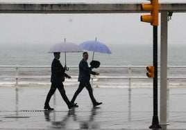 Dos personas pasean por el Muro de Gijón durante las constantes lluvias caídas el pasado miércoles.