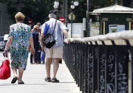 Una pareja de personas de avanzada edad pasea por la calle.