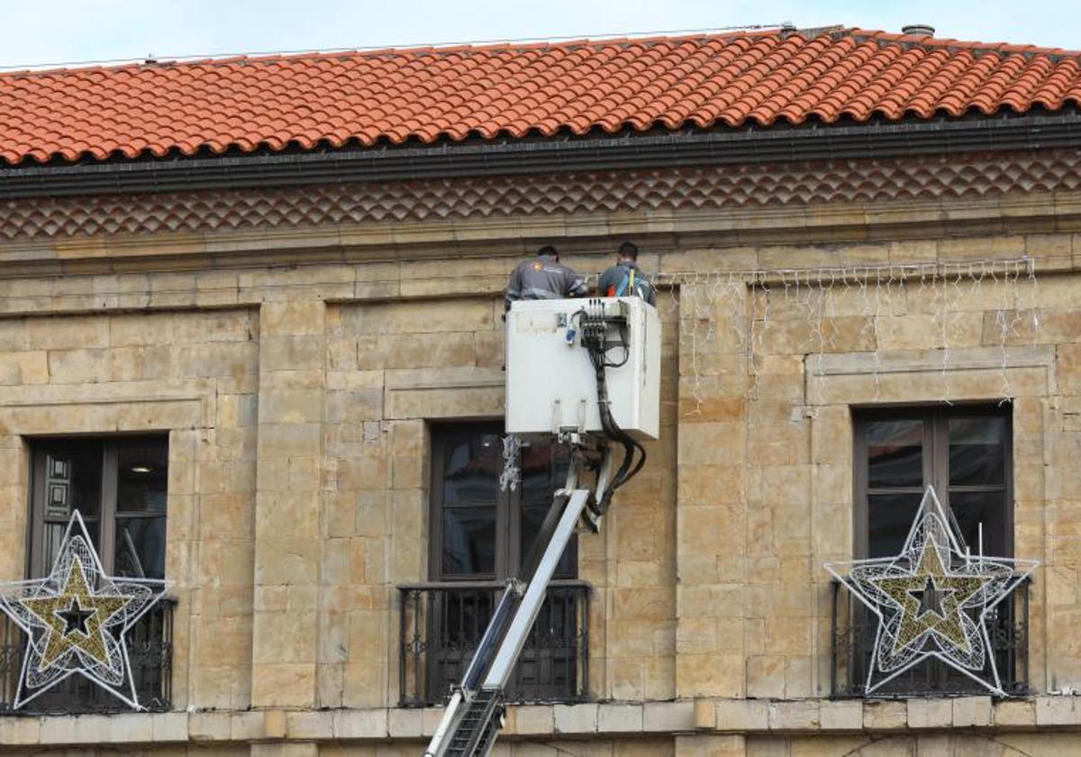 Dos operarios colocando las luces navideñas otro año.