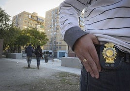 Un policía secreta muestra su placa en un barrio conflictivo.