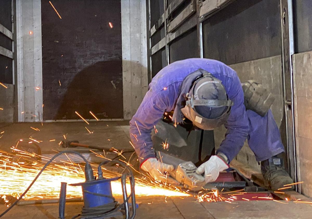 Un soldador repara la plataforma de un camión en un taller de Gijón.