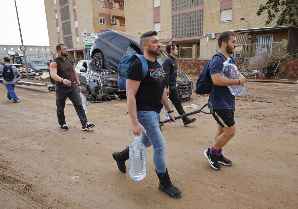 Varios residentes llevan garrafas de agua a la entrada de la localidad de Paiporta, Valencia, este jueves.