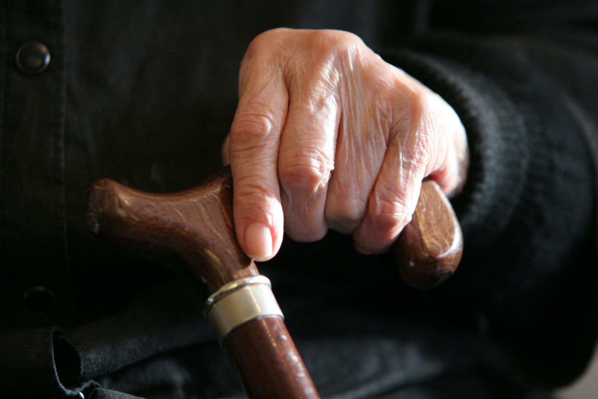 Una persona mayor sostiene un bastón.