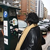 Una mujer se dispone a introducir una moneda en un parquímetro en El Carbayedo.