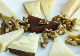 Un plato de queso con nueces y membrillo.