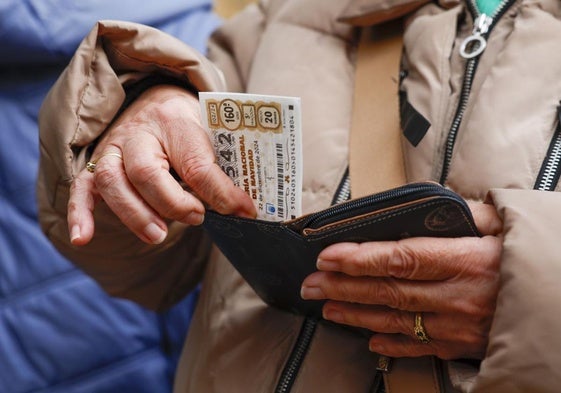 Una mujer guarda su décimo de la Lotería de Navidad.