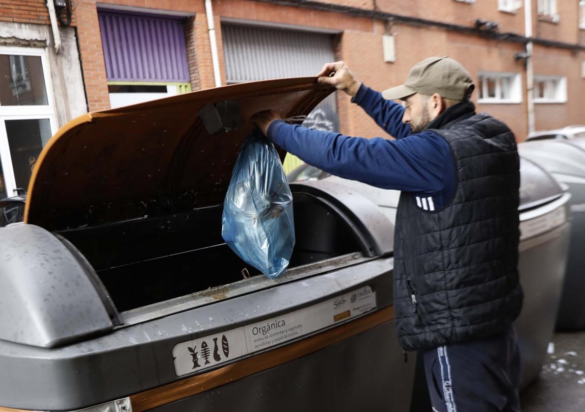 Un hombre deposita restos orgánicos en uno de los contenedores marrones de Gijón.