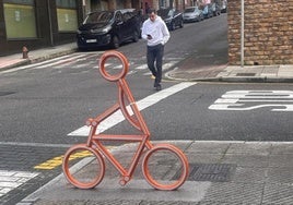 La silueta de un ciclista a punto de cruzar un paso de cebra en una calle de Laviana.