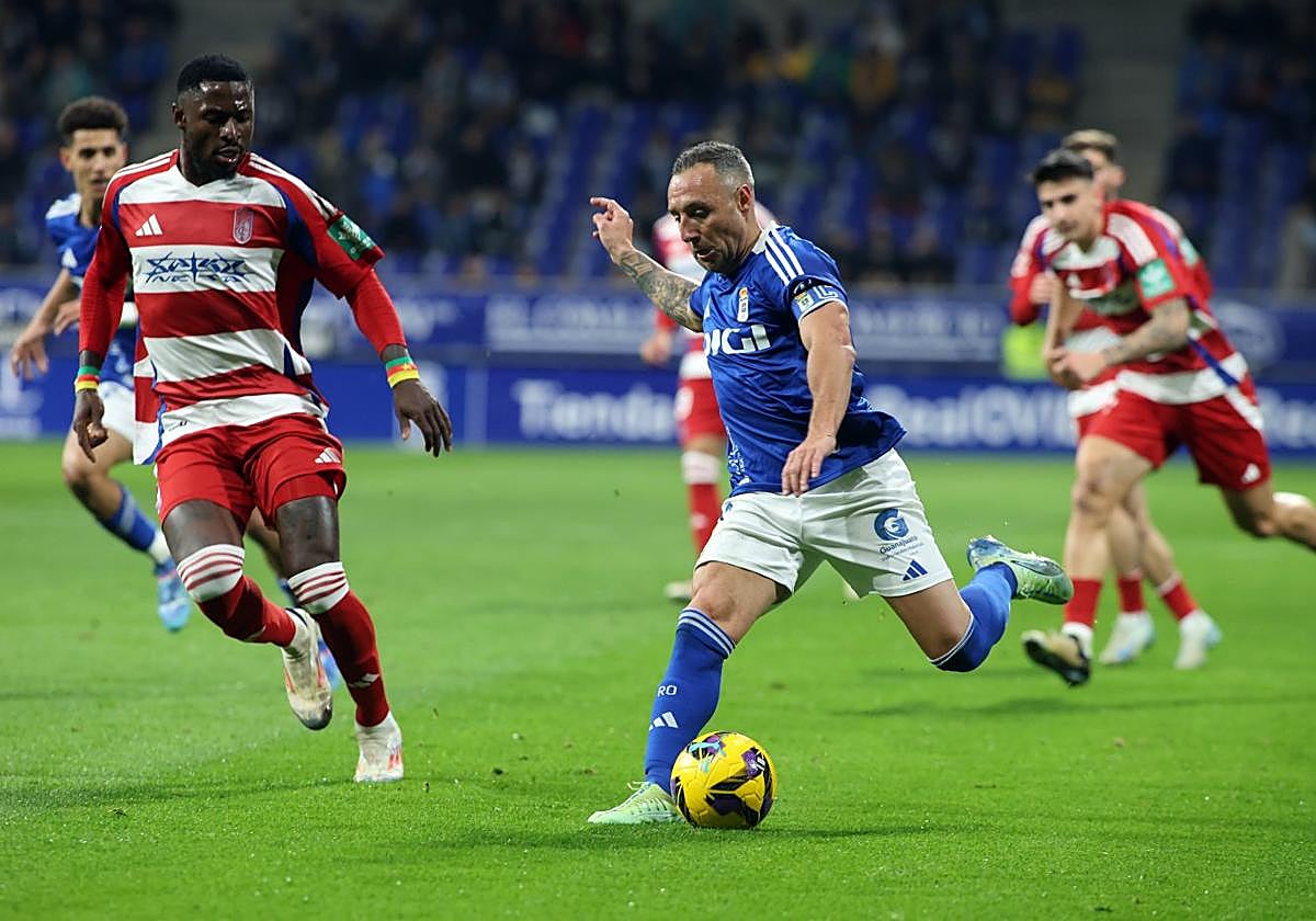 El capitán del Real Oviedo, Santi Cazorla, trata de realizar un centro ante la presencia de Hongla durante el partido frente al Granada en el Carlos Tartiere.